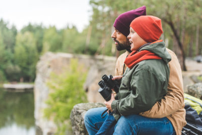 Image d'un homme tenant un enfant ; l'enfant tient des jumelles et ils regardent tous les deux vers la gauche.