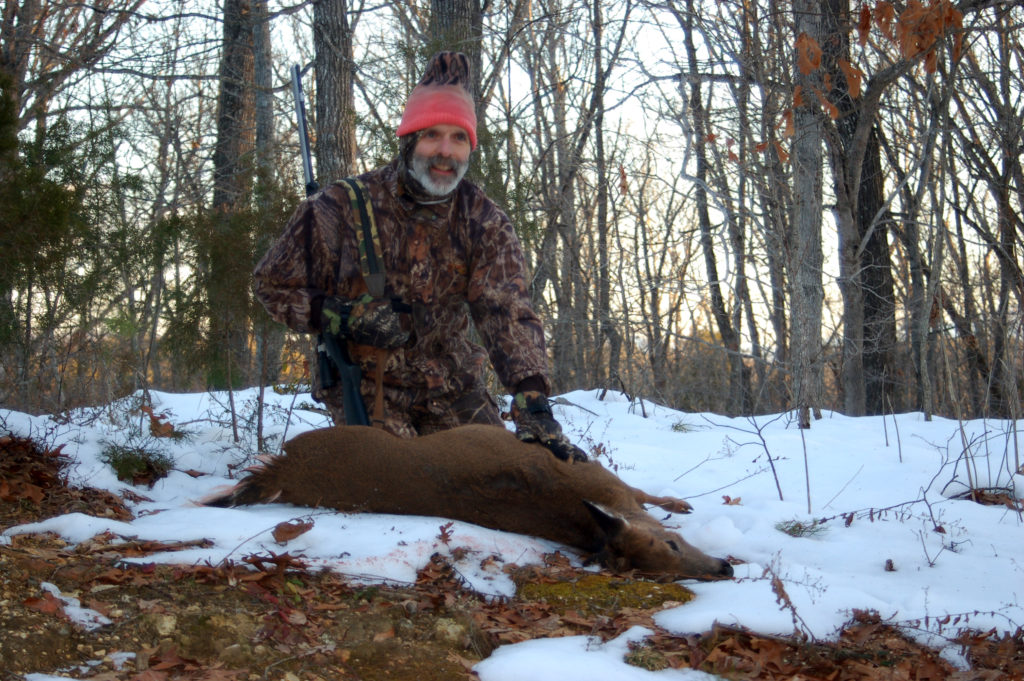 Image d'un homme posant avec un cerf qu'il a tué dans la neige.