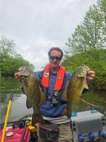 Pêcheur sur un bateau transportant deux black-bass à petite bouche provenant de la rivière North Fork Holston.