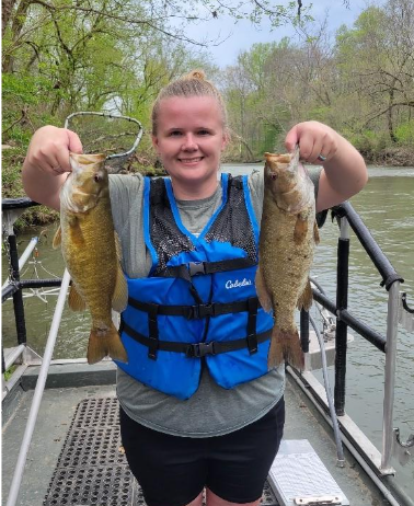 Pêcheur sur un bateau tenant deux poissons de la rivière Powell.