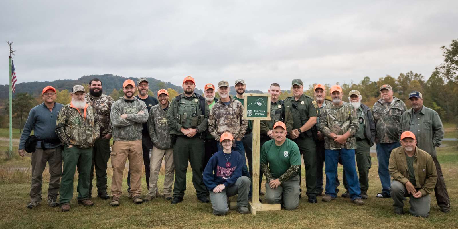 Un groupe de personnes ( 20 ) posant comme un groupe avec un panneau indiquant "Elk Weigh Station."