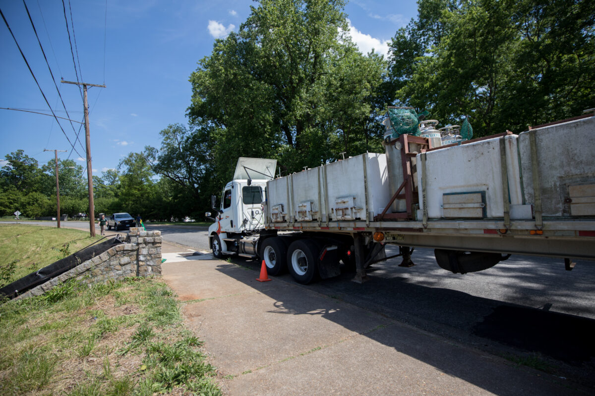 Un camion de stockage rempli de citernes est garé à côté d'un escalier en pierre pour être chargé.