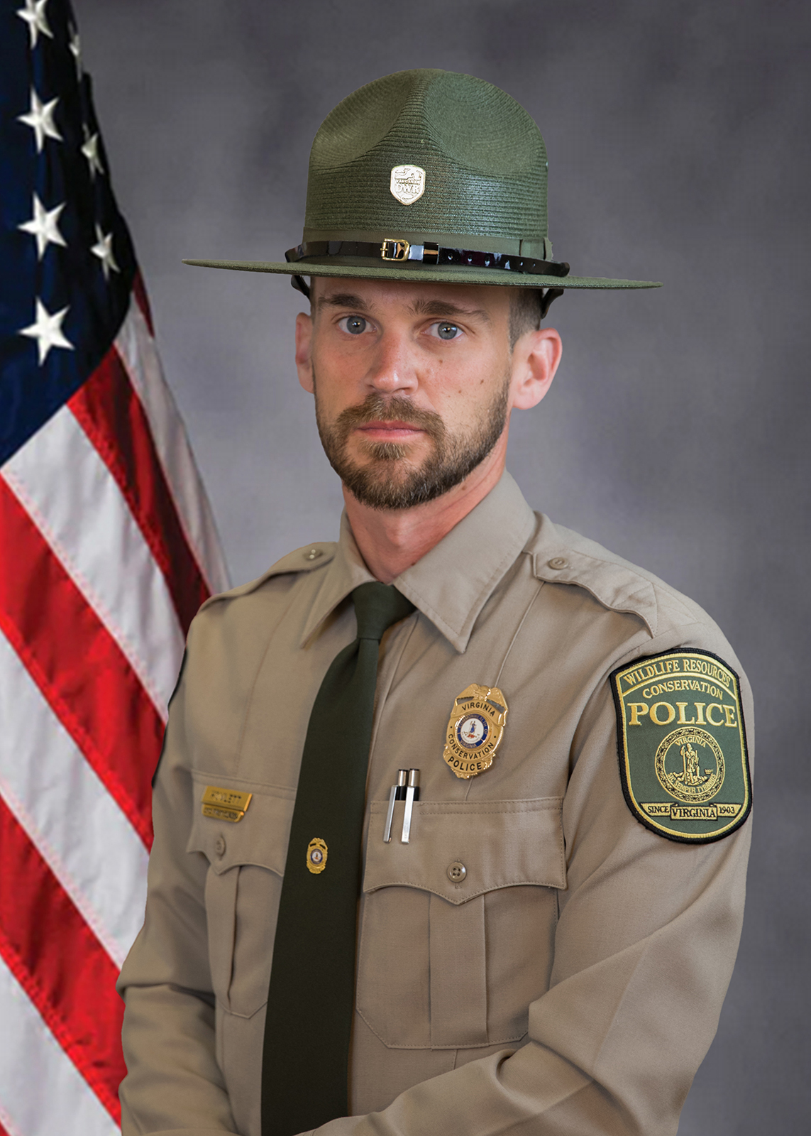 Photo d'un agent de la police de la conservation posant avec un drapeau américain.
