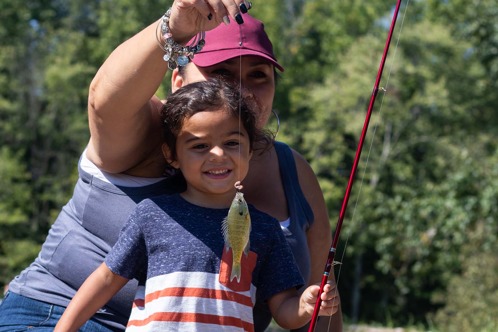 Une mère et sa fille souriant et tenant un poisson sur une ligne