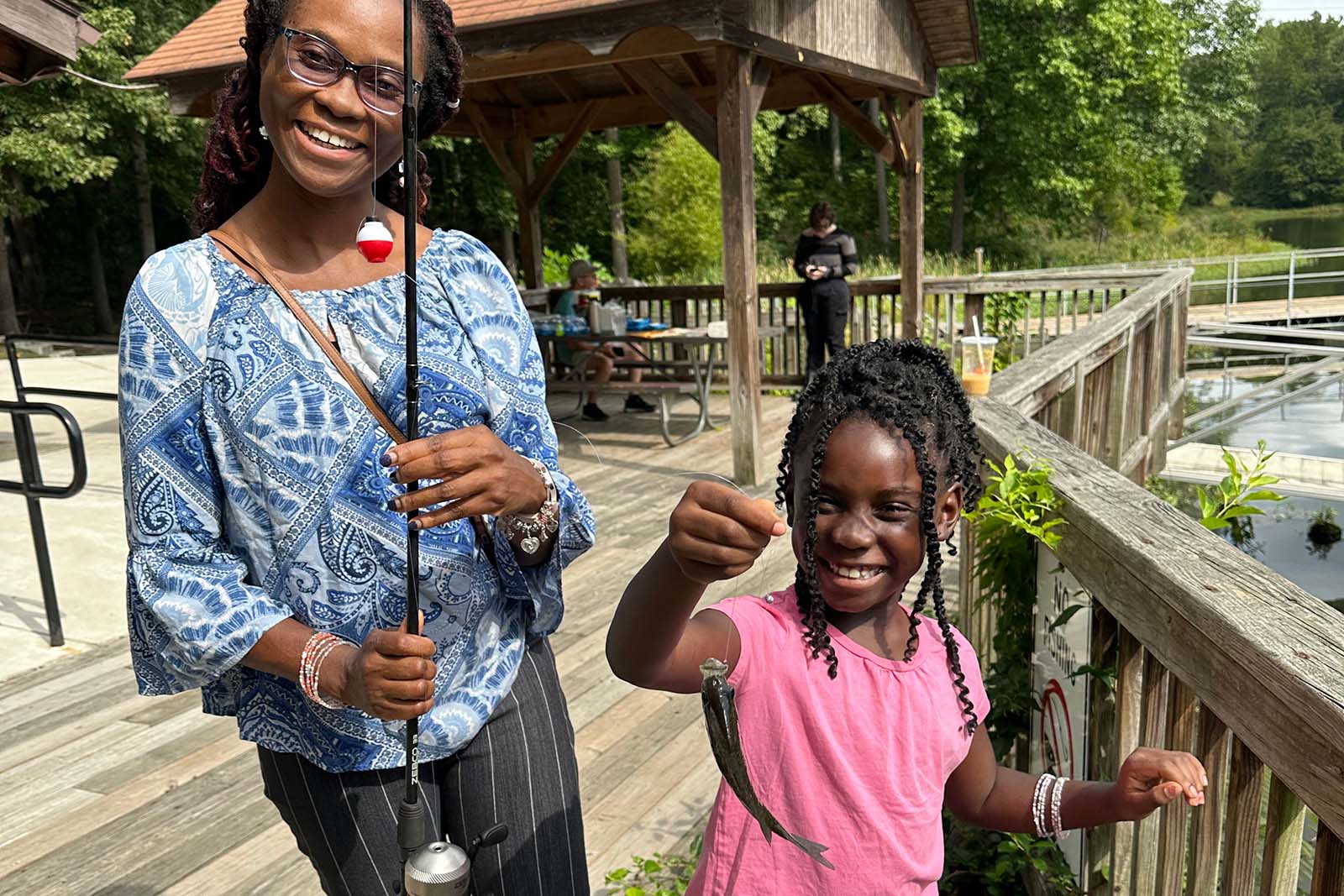 Une femme et un enfant tenant une canne à pêche et un poisson
