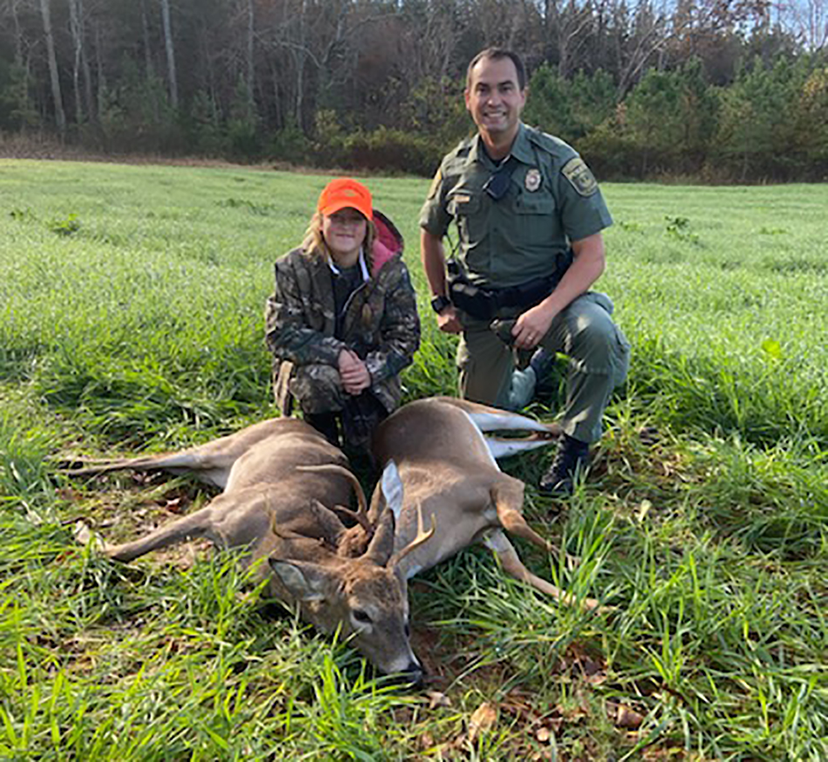 Une image du CPO Cory Harbor et d'un jeune chasseur posant devant deux cerfs morts.