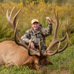 Homme souriant avec son animal tué, un élan.