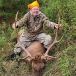 Une personne posant avec un élan mort.