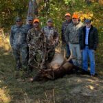 Un groupe de sept hommes posant avec un élan tué.