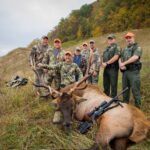 Huit hommes posant avec un élan tué.