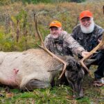 Deux hommes posant avec un élan mort.
