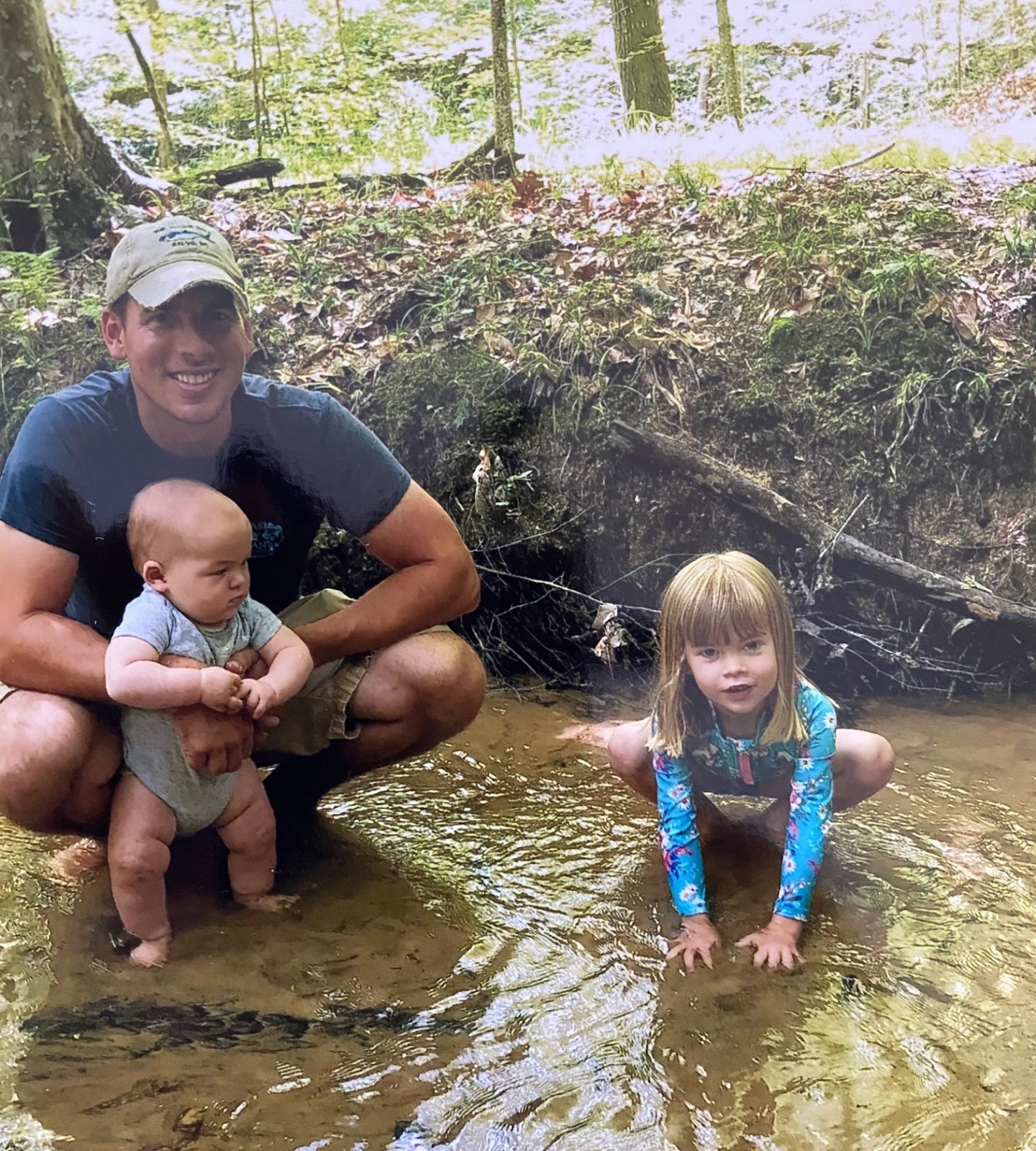 Image de deux enfants et de leur père dans un ruisseau