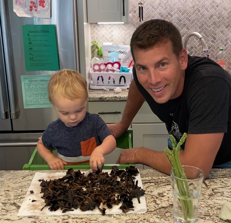Image d'un jeune garçon à côté d'un tas de champignons et de son père.