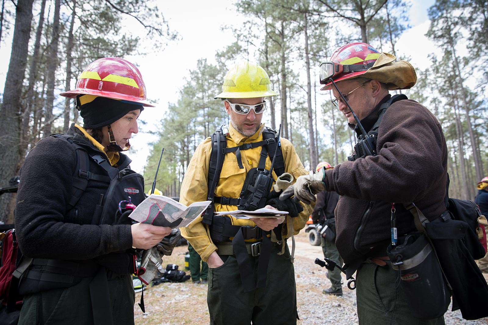 Trois membres de l'équipe de pompiers du DWR se réunissent pour examiner le plan de brûlage dirigé de la journée.