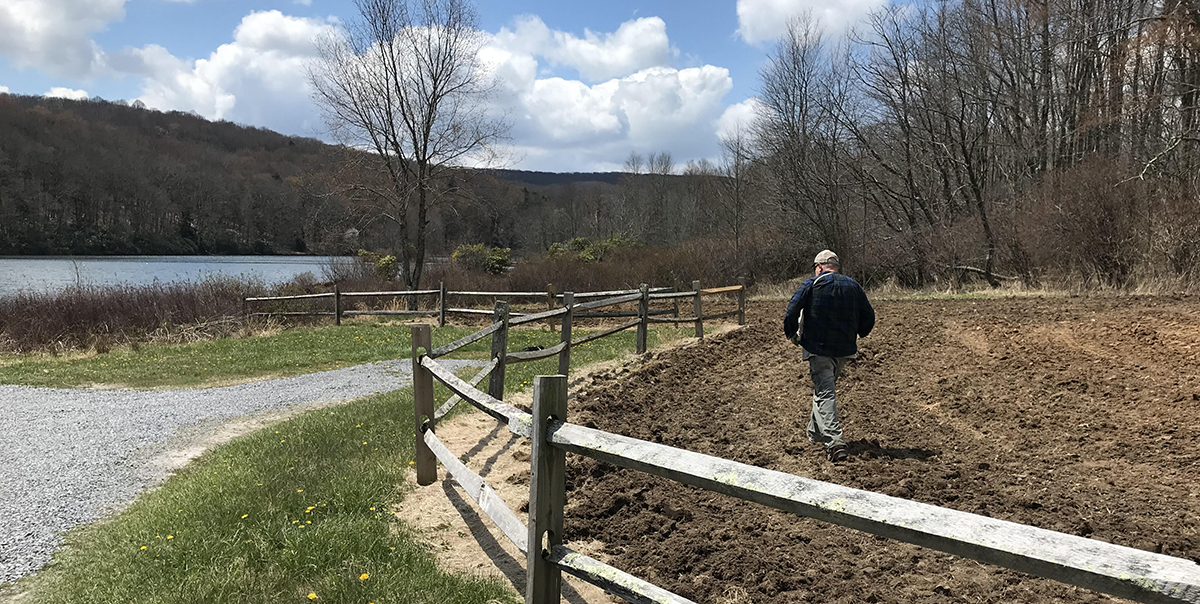 Un membre du personnel du DWR distribue de l'engrais et des semences sur le sol désherbé.