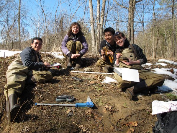 Quatre étudiants en conservation posant pour une photo dans une forêt de feuillus ; deux d'entre eux tiennent des tortues des bois et deux autres ont des carnets de notes de l'enquête sur les tortues des bois à laquelle ils ont participé.