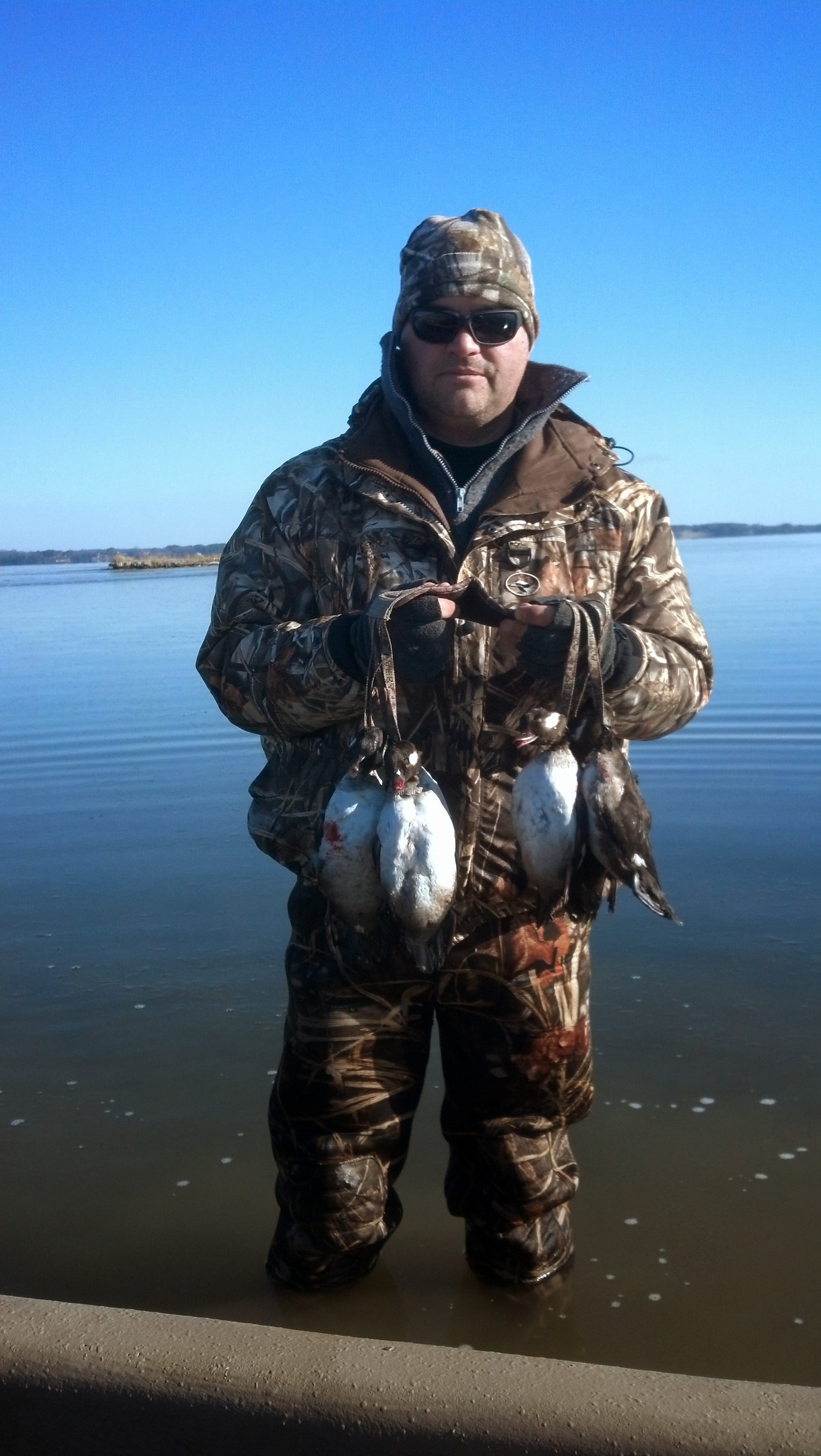 Image d'un homme dans l'eau glacée tenant un groupe de canards morts.