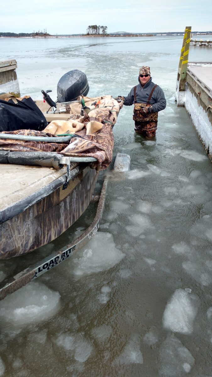 Image d'un homme dans l'eau glacée aidant à amarrer un bateau.