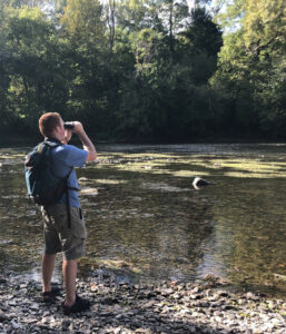 Image d'un homme avec des jumelles regardant un plan d'eau.