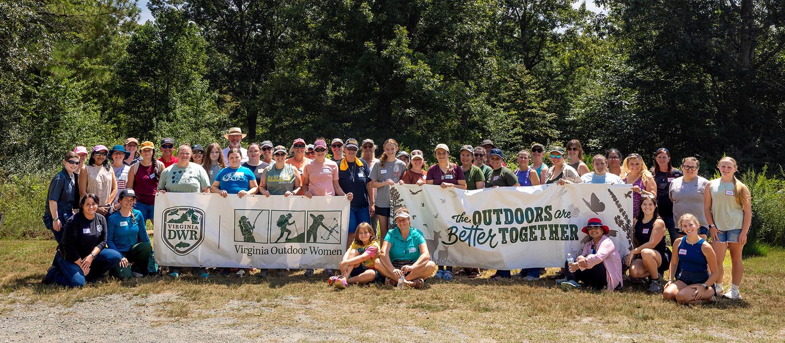 Une photo d'un groupe de femmes debout tenant une bannière sur laquelle on peut lire "The Outdoors Are Better Together."