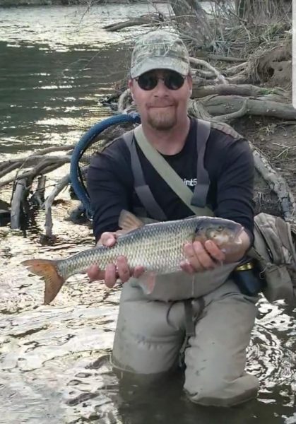 Une image de Jerry Hall dans une zone humide tenant le record de taille d'un dauphin pour l'État.