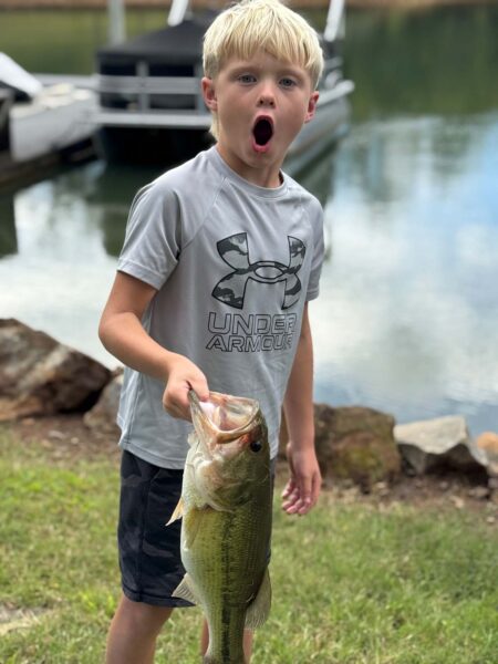 Un jeune garçon excité tenant un poisson par la bouche.