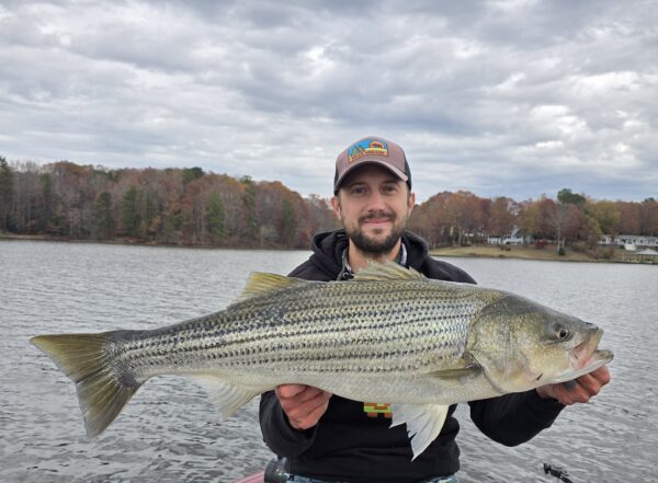 Le pêcheur Derek Merrick tient un bar rayé devant le lac.