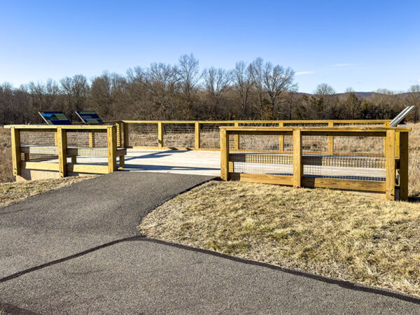 Bureau d'observation en bois au bout d'un chemin asphalté surplombant une zone humide en hiver.