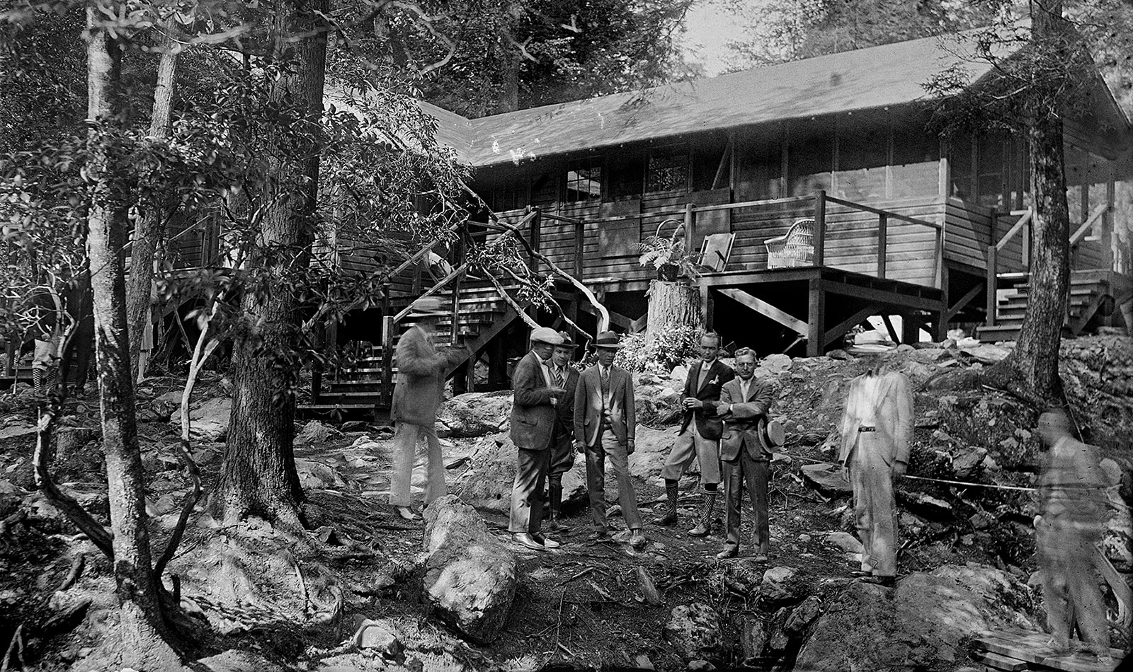 Photo en noir et blanc d'un groupe de personnes portant des vêtements de l'époque 1930devant The Brown House, une résidence en bois construite sur un point de vue de la rivière Rapidan.