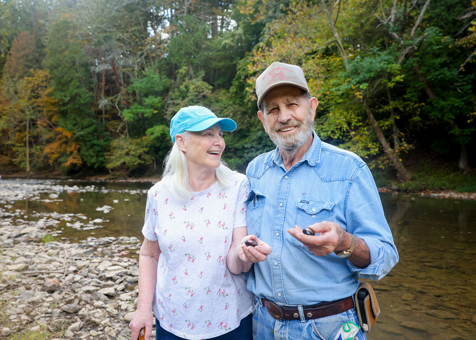 Photo d'un homme et d'une femme tenant des moules d'eau douce et se tenant devant une rivière.
