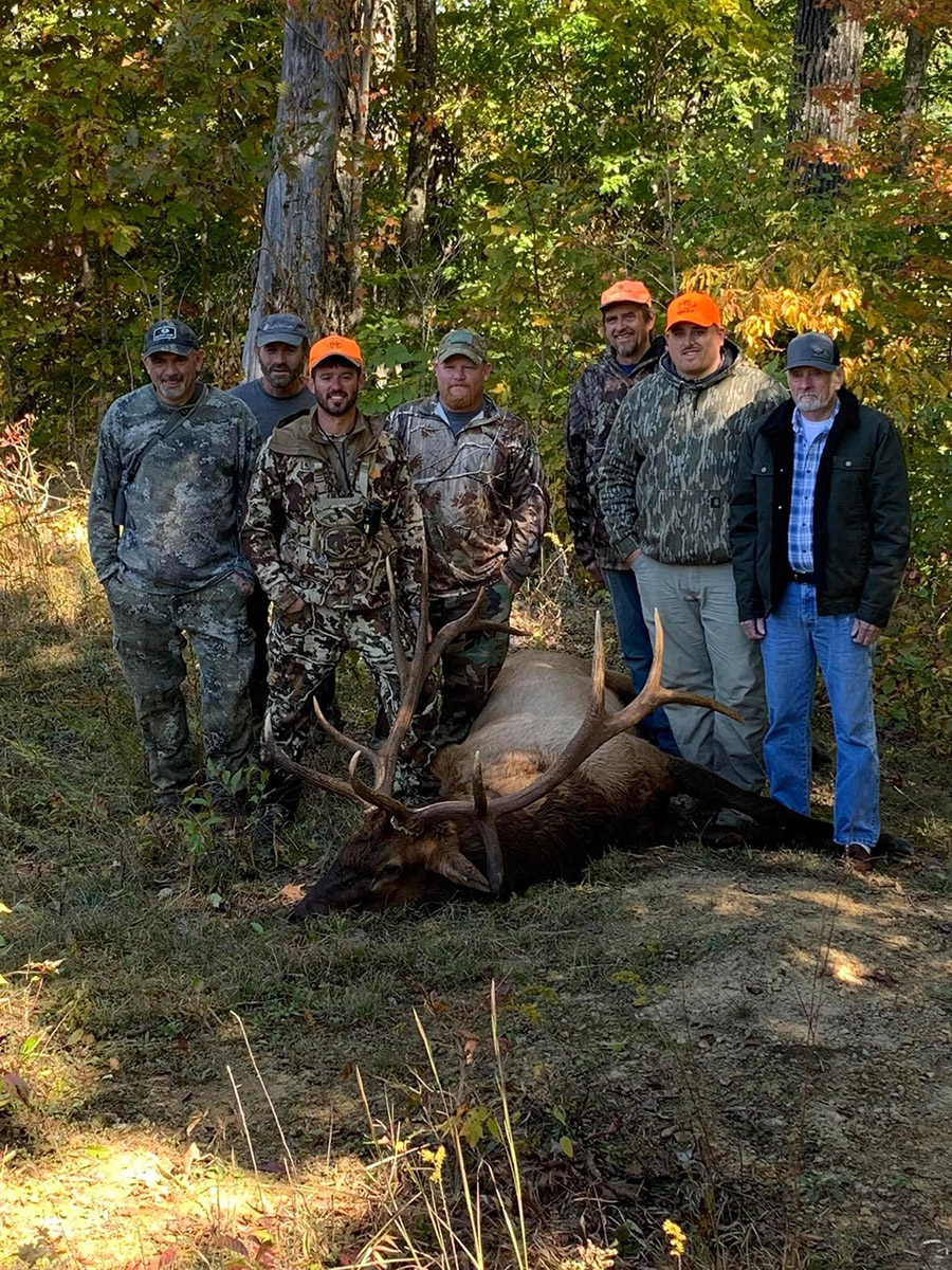 Un groupe de sept hommes à côté de l'élan mâle qu'ils ont capturé