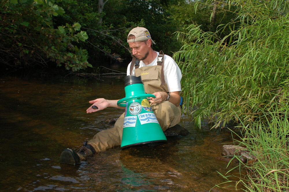 Image d'un biologiste qui a utilisé un dispositif pour regarder dans l'eau en tenant une moule épineuse de James qu'il avait attrapée.
