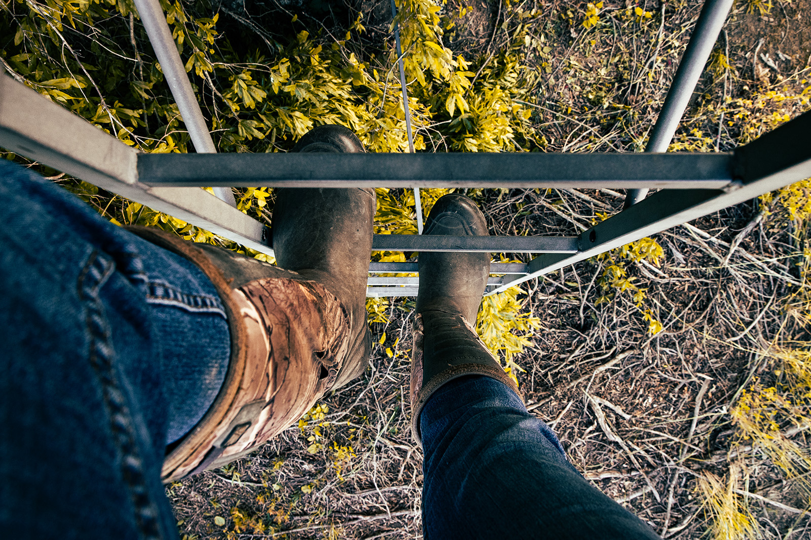 Photo en gros plan de pieds bottés grimpant l'échelle d'un mirador.
