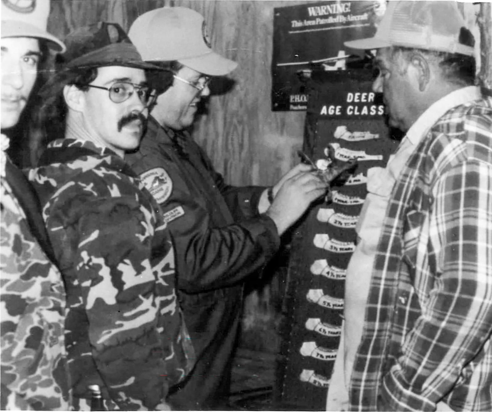 Une vieille image en noir et blanc montrant des chasseurs mesurant des mâchoires de cerf.