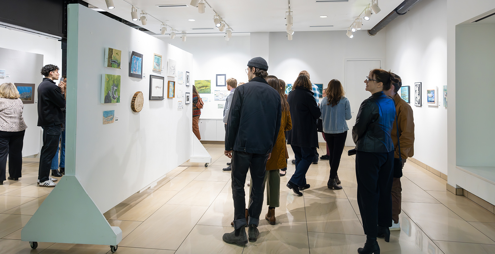 Photo d'un groupe de personnes regardant des œuvres d'art accrochées aux murs.