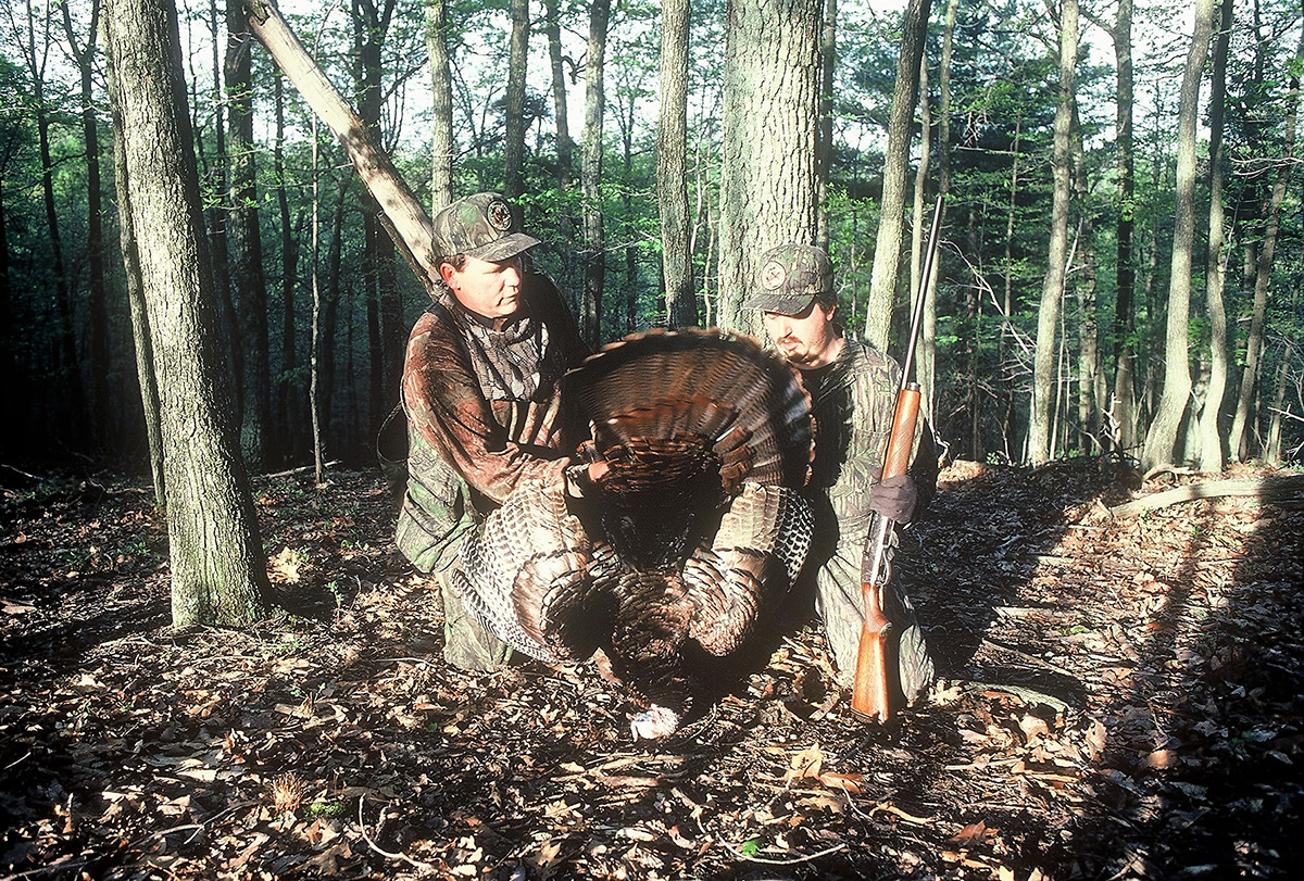 Image d'un dindon mâle et des deux chasseurs qui l'ont abattu.