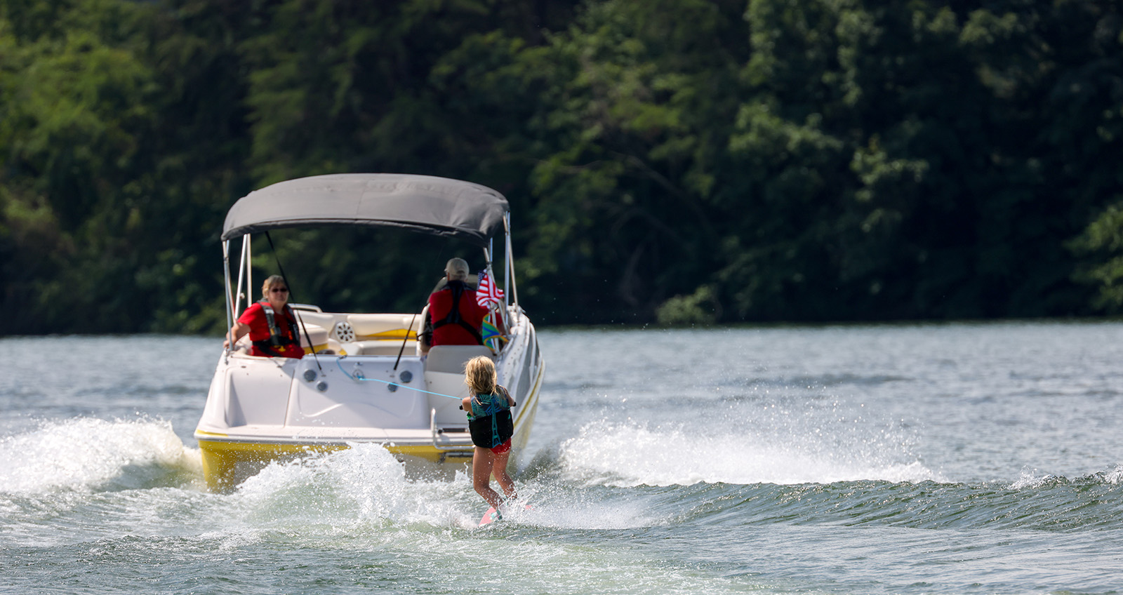 Photo de l'arrière d'un bateau tirant un jeune skieur nautique.