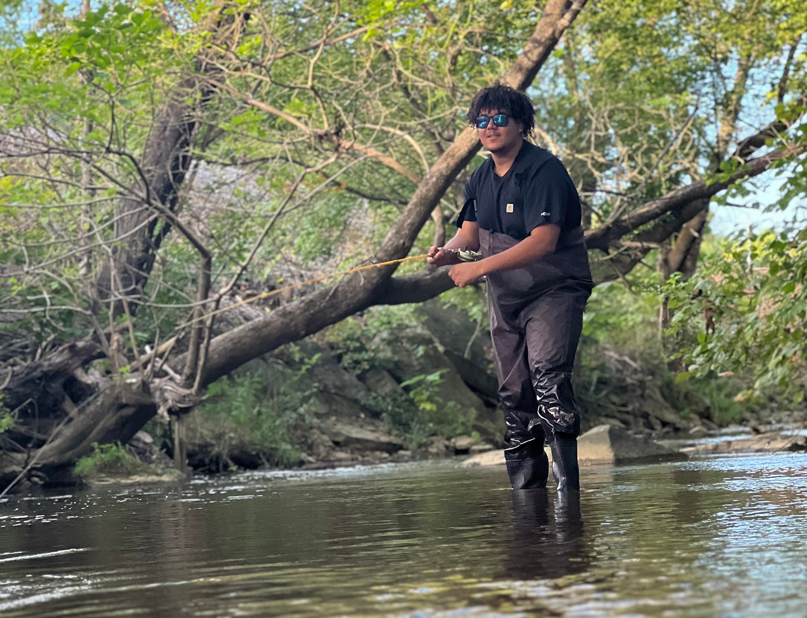 La photo d'un homme en cuissardes se tenant debout jusqu'à la cheville dans un ruisseau avec une canne à pêche.