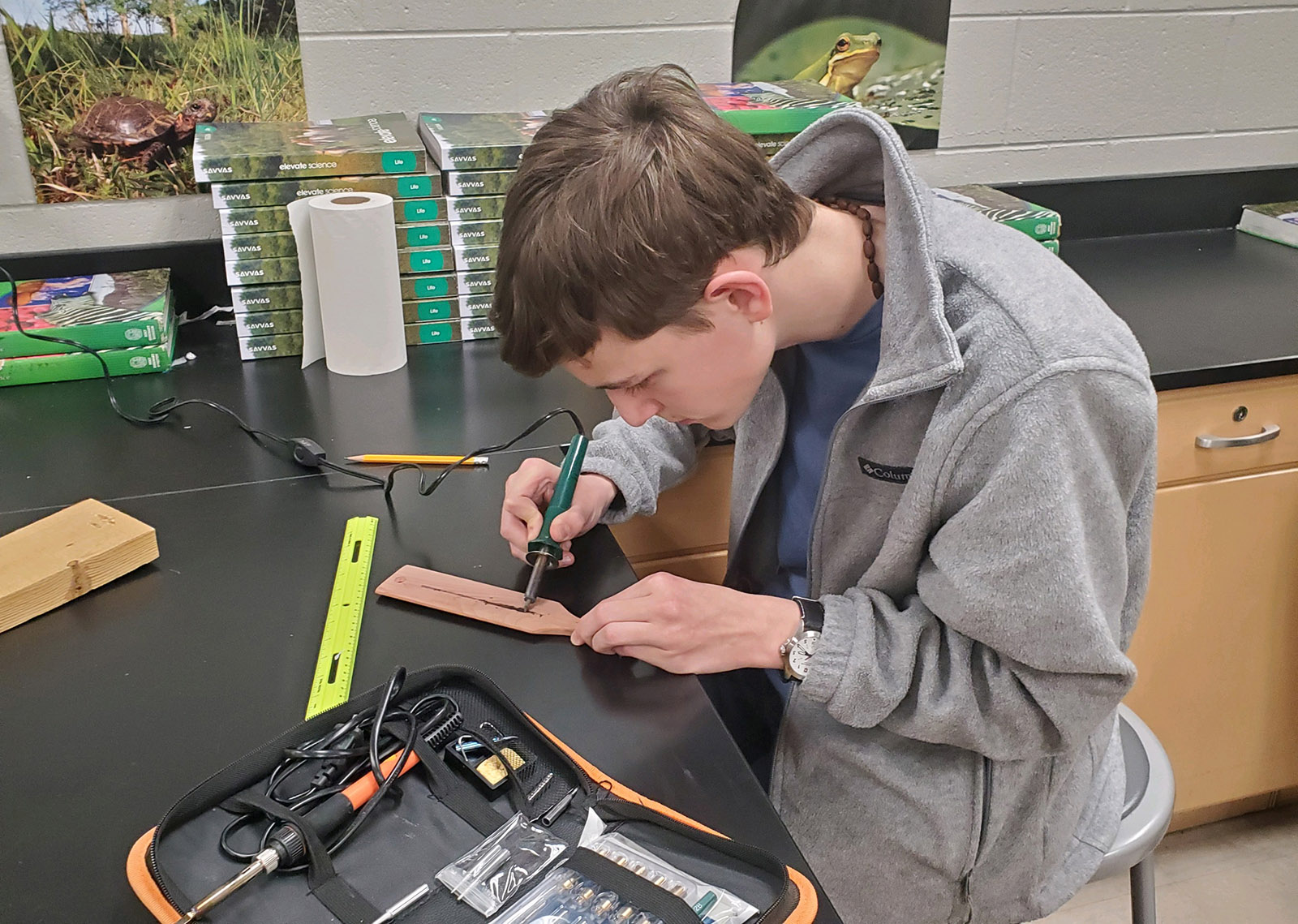 Photo d'un jeune homme à une table de travail, utilisant un outil à bois sur une palette d'appel à la dinde.