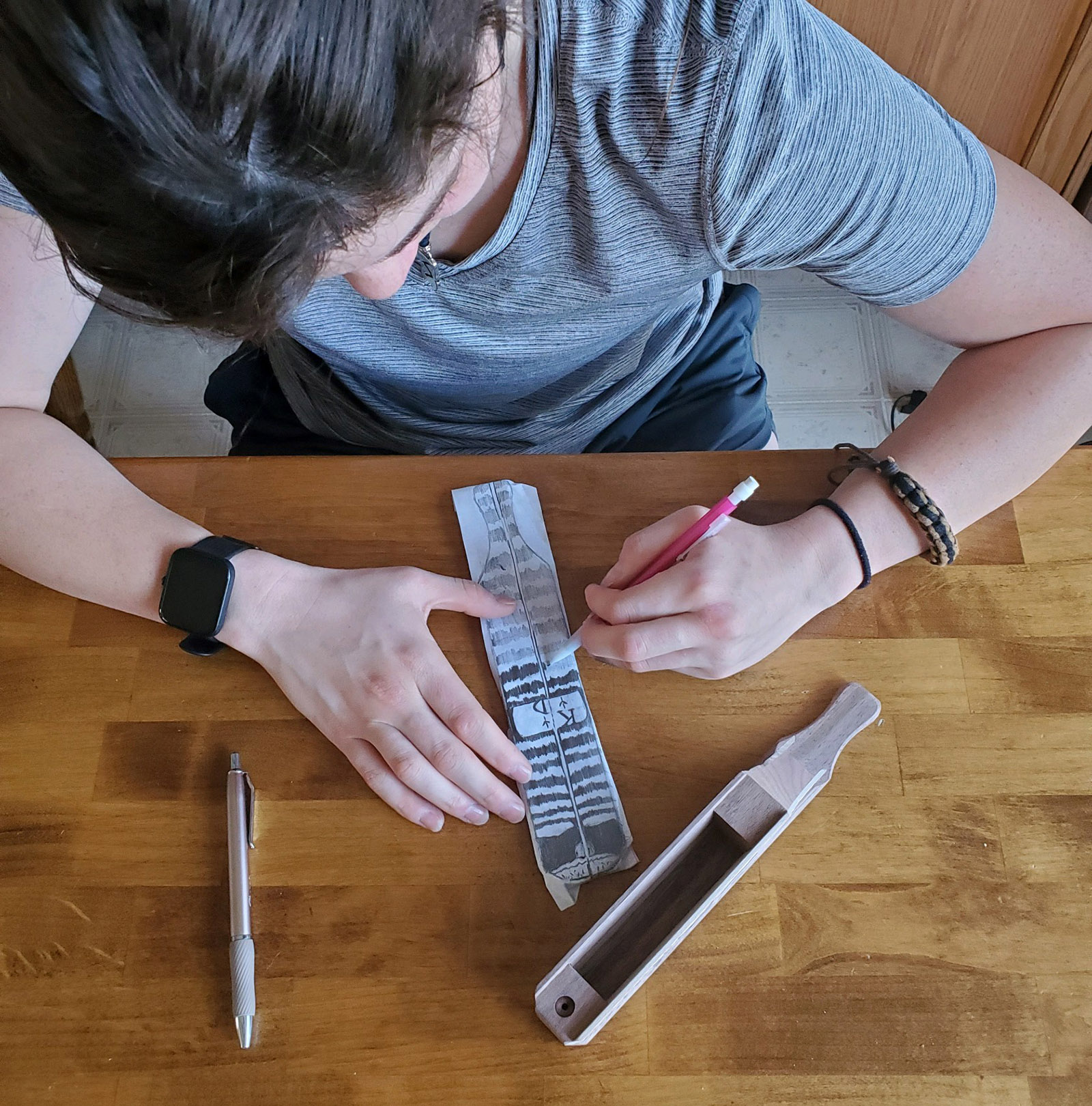 Une photo d'une jeune fille traçant un motif sur du papier avec un appeau à dinde à palette posé à côté d'elle sur la table.