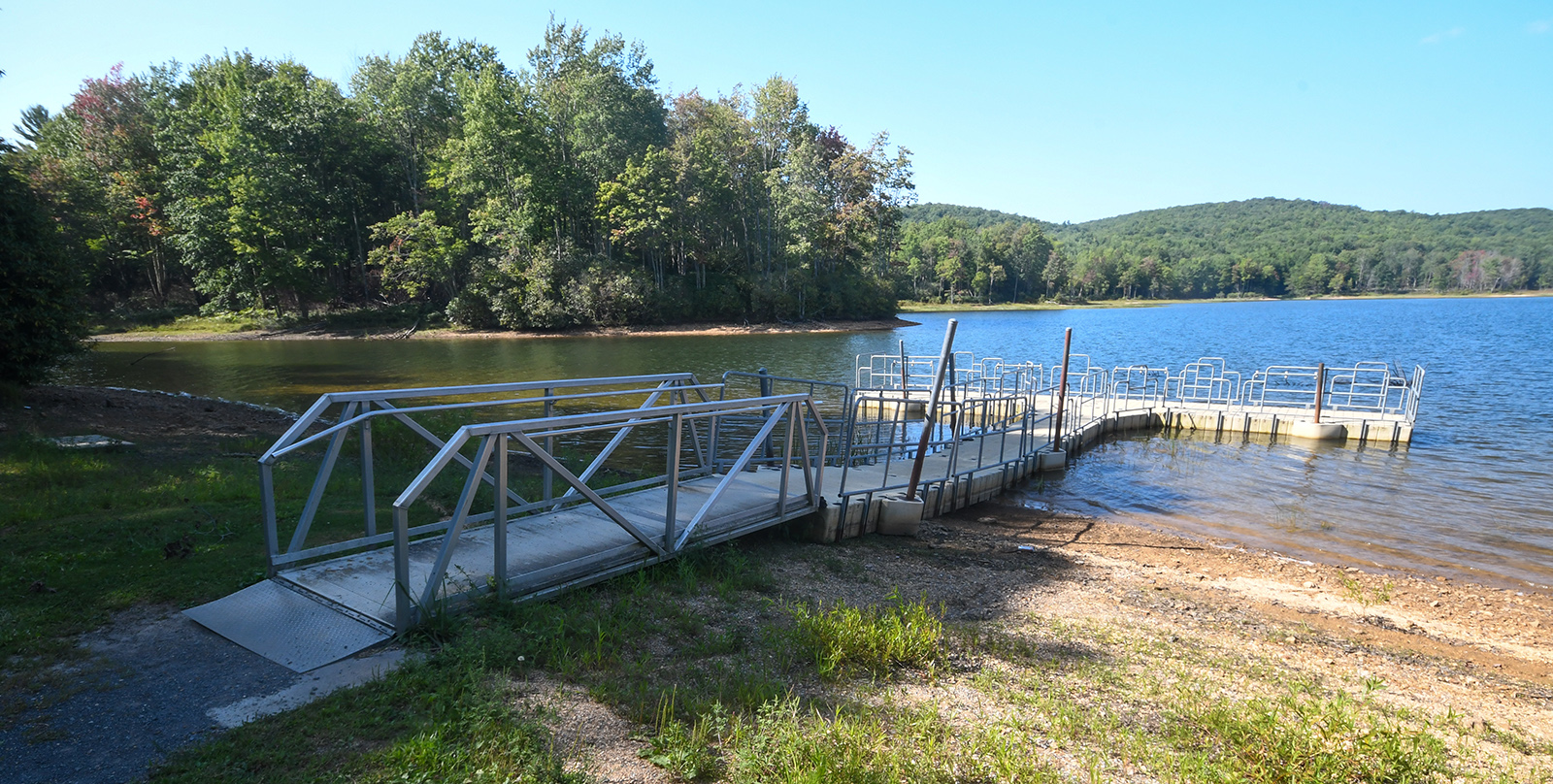 Une photo d'un quai de pêche métallique accessible qui s'avance sur un grand lac.