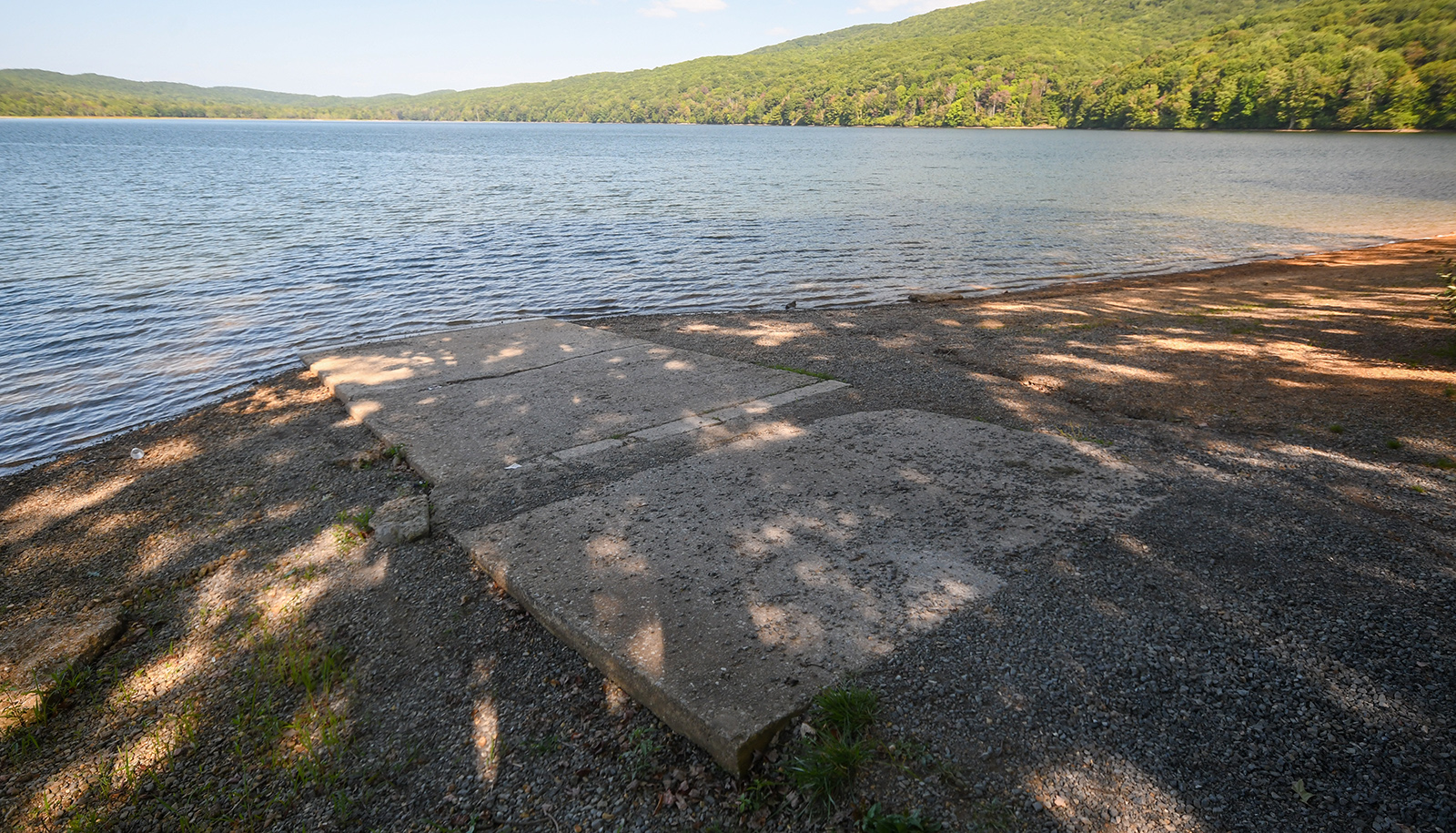 Une photographie représentant une série de dalles de béton posées sur du gravier menant à l'eau d'un lac.