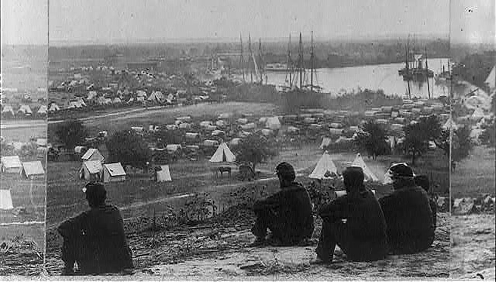 Image de quatre hommes assis sur une colline surplombant la baie de Cumberland, à l'extérieur d'une colonie militaire pendant la guerre civile.