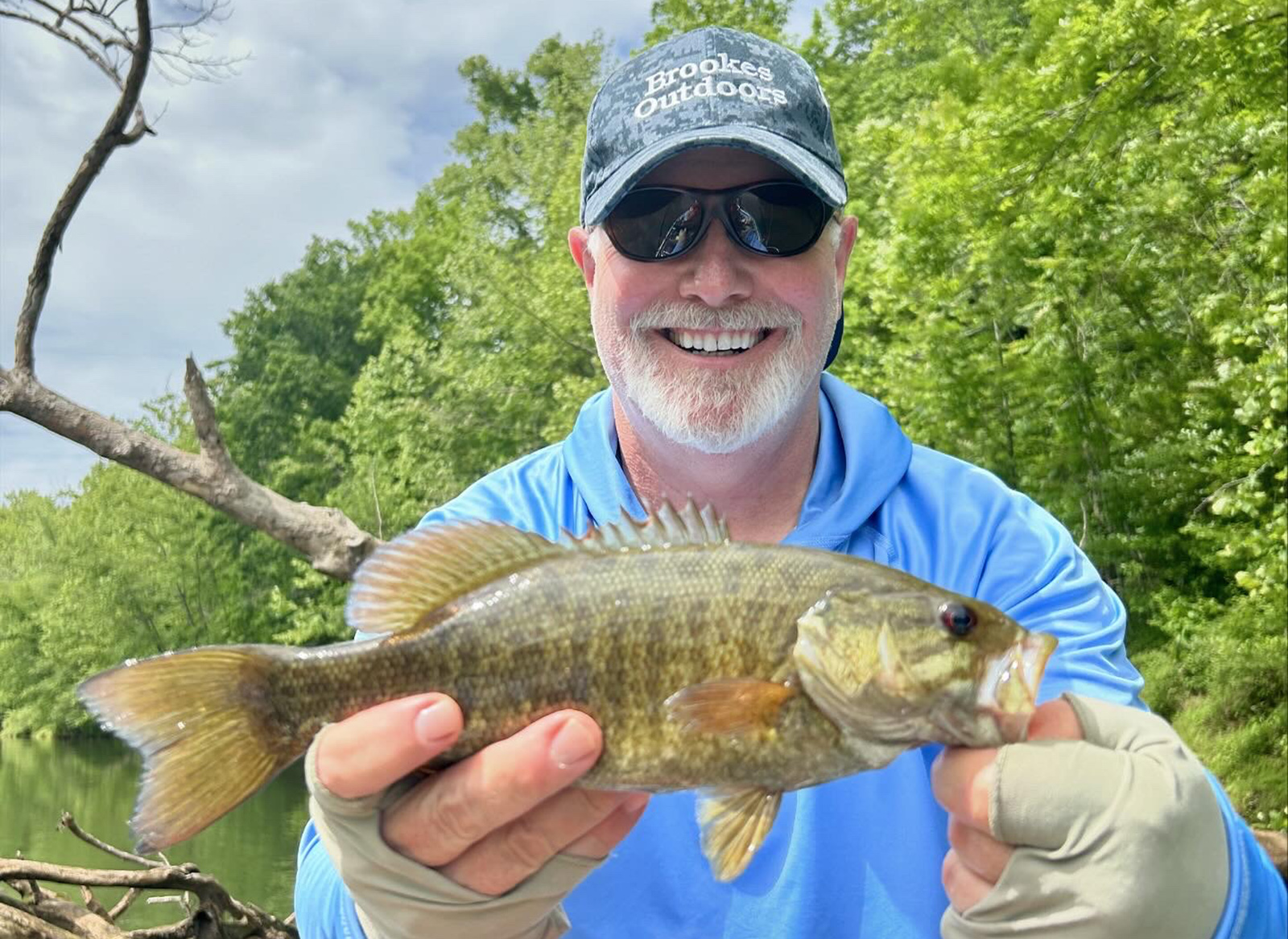 Un homme tient un achigan à petite bouche pour une photo.