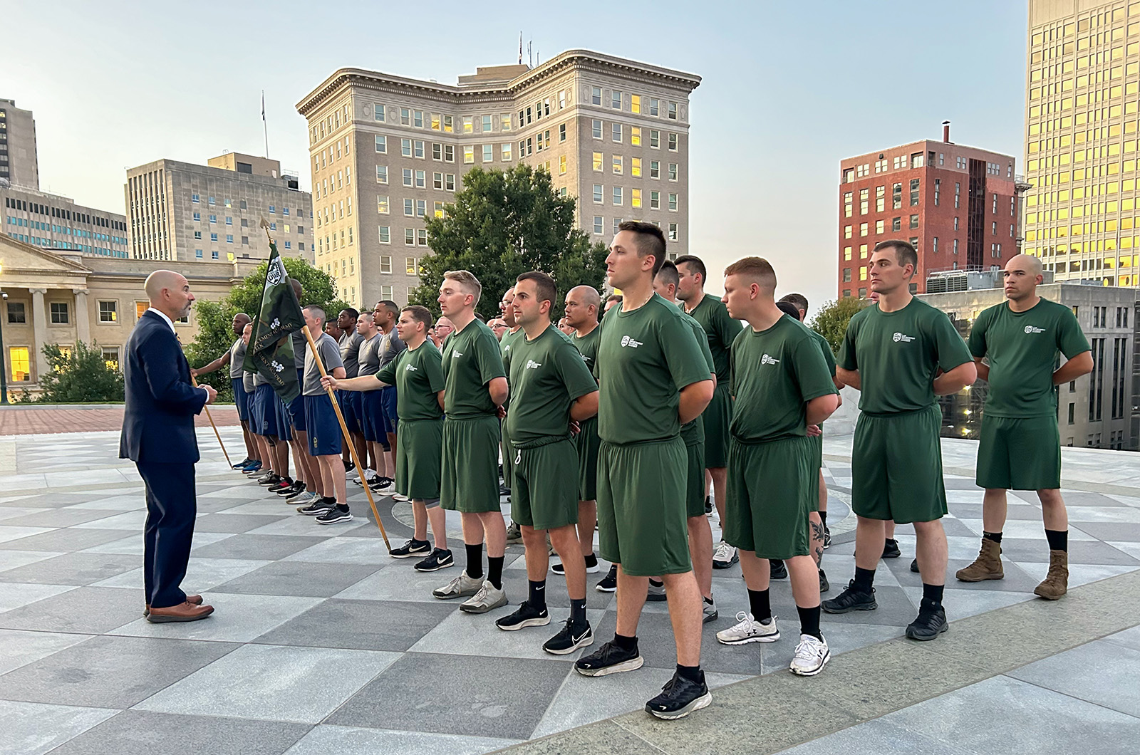 Un groupe de jeunes hommes et de jeunes femmes au garde-à-vous s'adressant à un homme en costume sur les marches du Capitole de Virginie.
