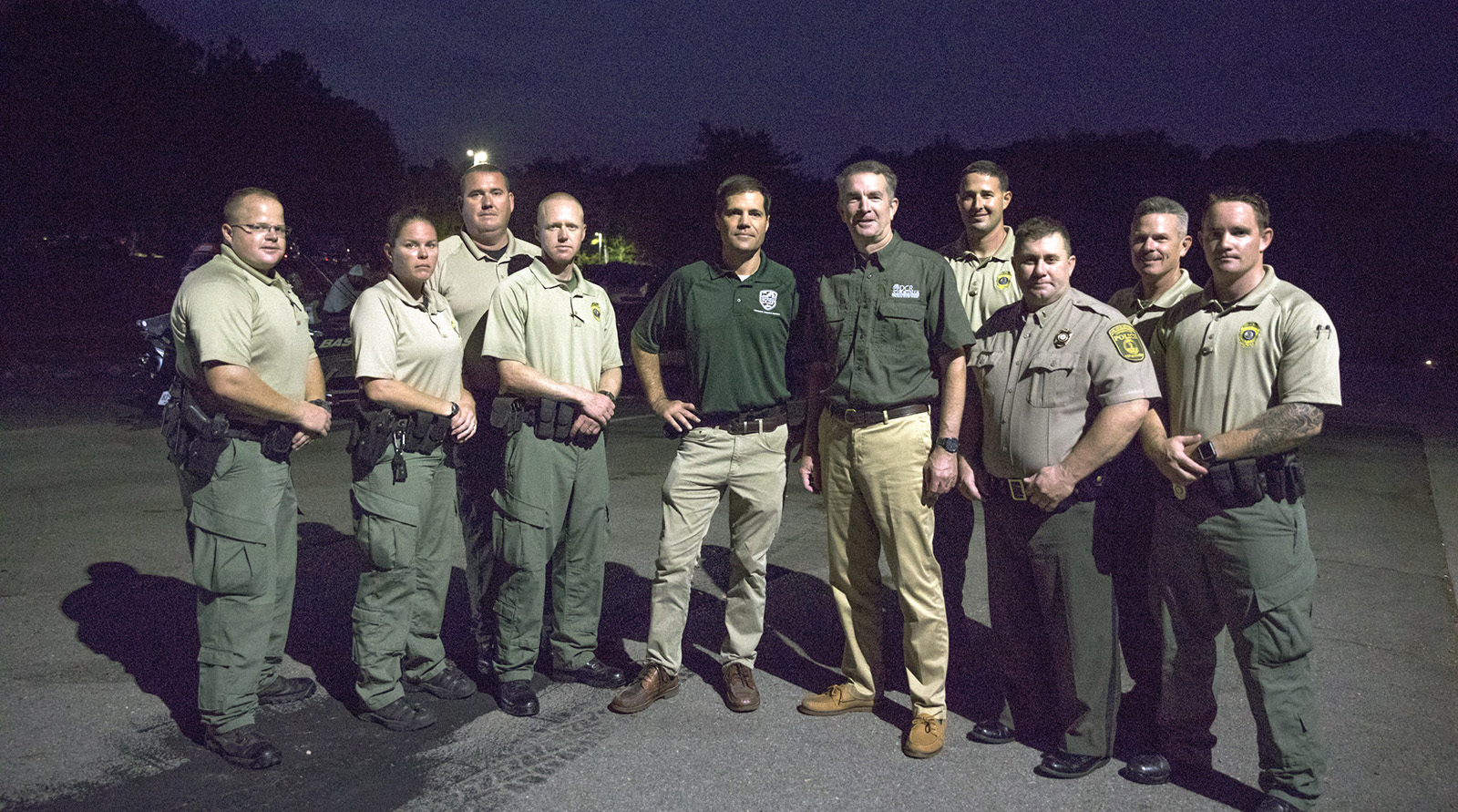 Une photo de Ryan Brown (au centre) et du gouverneur Northam avec huit agents de la police de conservation en uniforme.