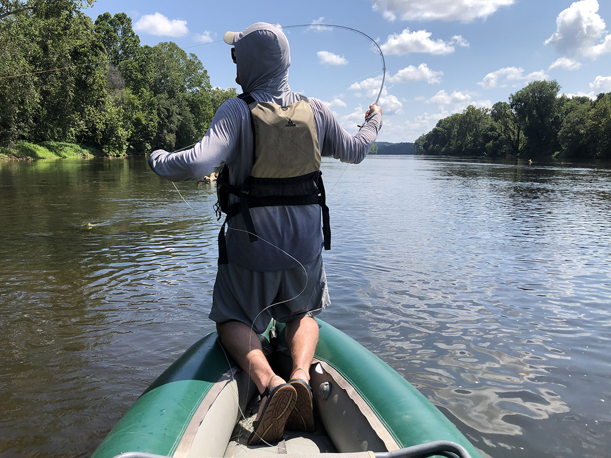 Image d'un homme sur un bateau vert pêchant l'achigan à petite bouche.