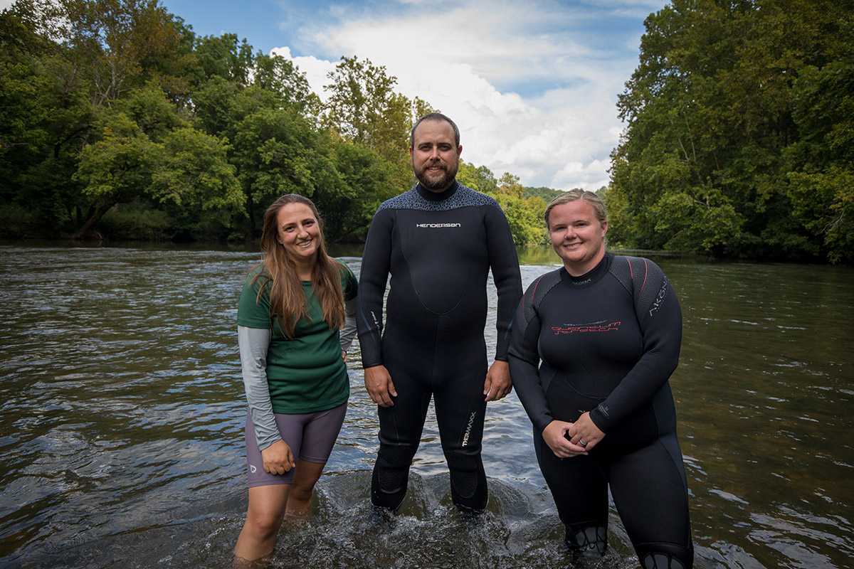 Une image d'un trio de personnes debout dans une rivière posant pour une image