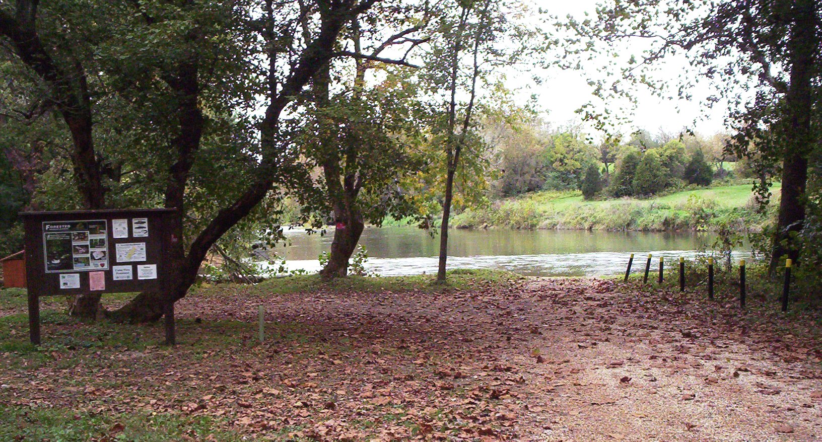 Image d'un lac menant à un site d'accès aux bateaux du DWR, avec un panneau d'affichage en bois au premier plan.