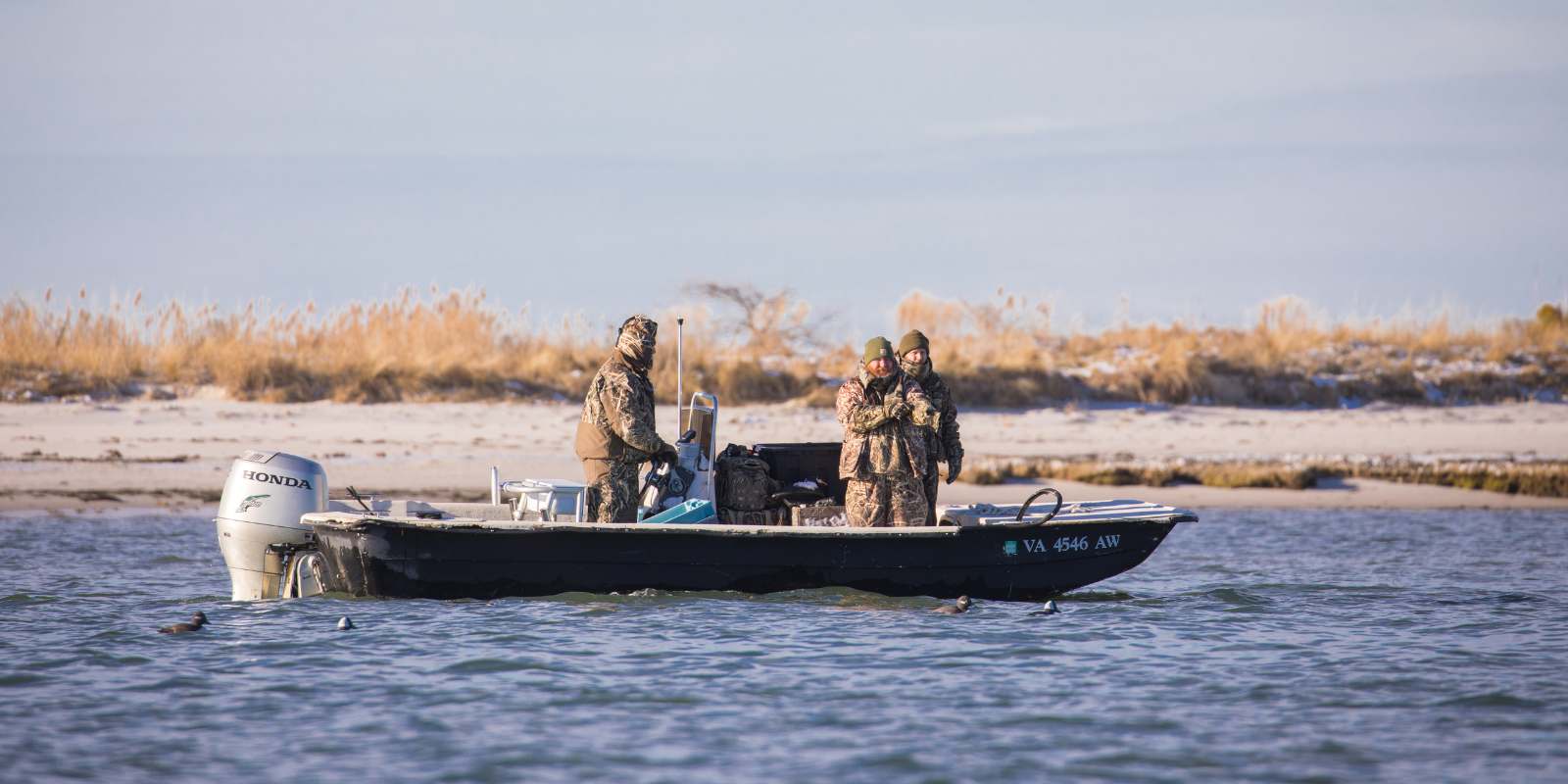 Trois personnes dans un bateau par une journée froide ayant des problèmes de moteur